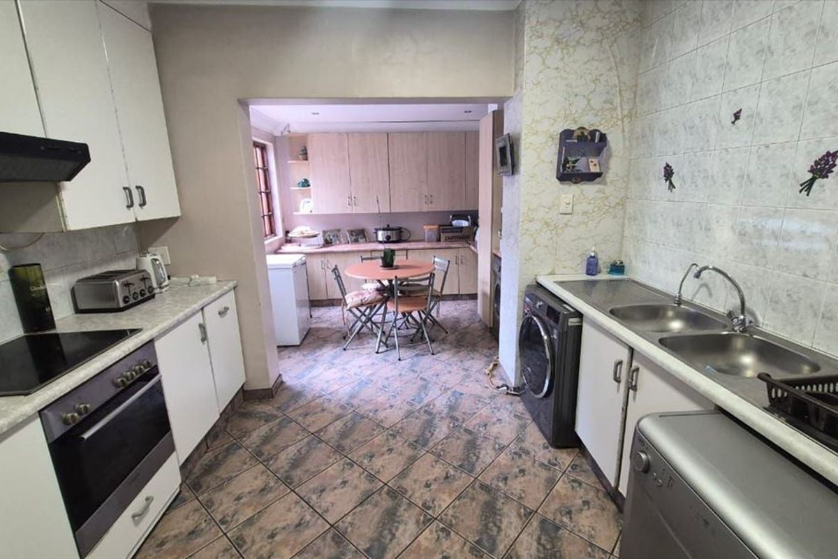 Functional kitchen featuring built-in cabinetry, laminate countertops, double bowl sink, and integrated cooking appliances with tiled flooring and splashbacks.