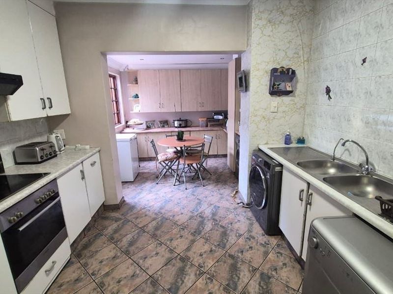 Functional kitchen featuring built-in cabinetry, laminate countertops, double bowl sink, and integrated cooking appliances with tiled flooring and splashbacks.