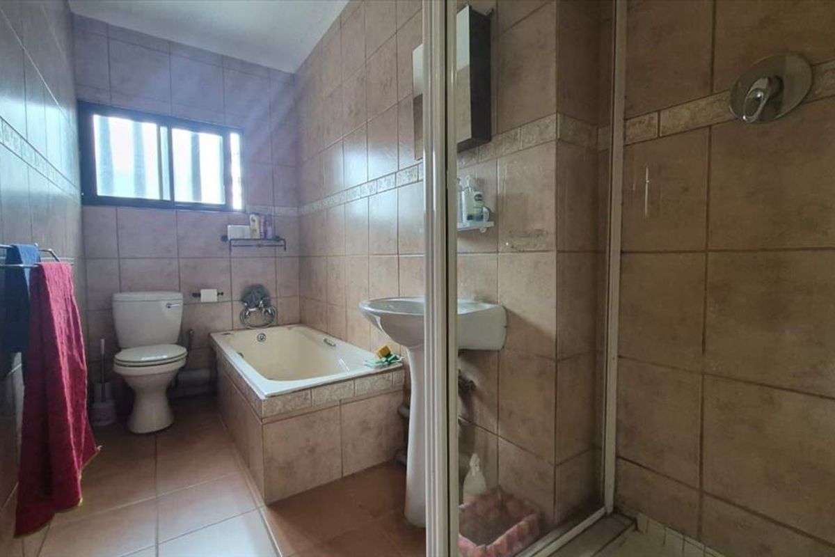 A functional bathroom featuring a pedestal basin, built-in bathtub, and a separate shower enclosure with full-height wall tiling.