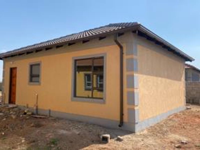 A newly constructed single-story house featuring a tiled roof, plastered exterior walls with corner detailing, and aluminium window frames.