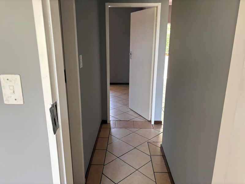 A functional hallway featuring neutral grey walls and tiled flooring, providing access to adjacent rooms within the apartment.