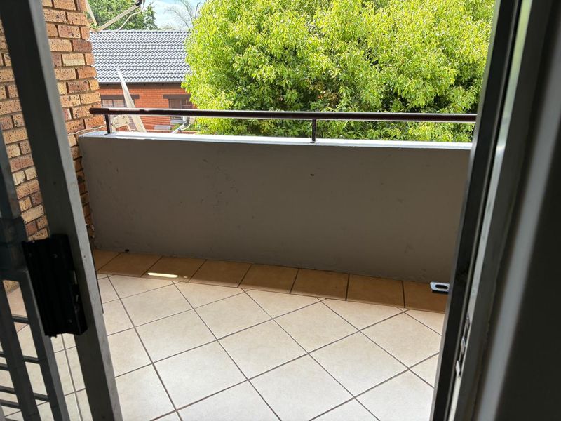A private balcony featuring tiled flooring and a metal balustrade, offering an outdoor space accessible from the apartment interior.