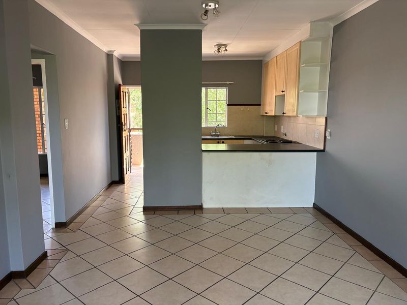 Open plan living and kitchen area featuring tiled flooring, built-in cabinetry, and a breakfast counter, providing a functional layout for modern apartment living.