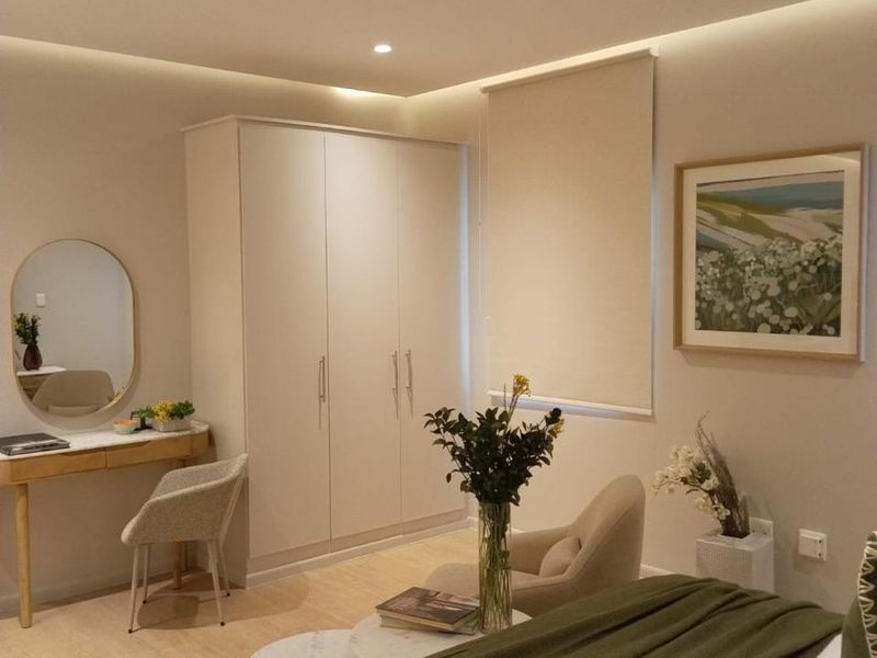 A well-maintained bedroom featuring neutral tones, built-in wardrobe storage, recessed ceiling lighting, and modern laminate flooring.