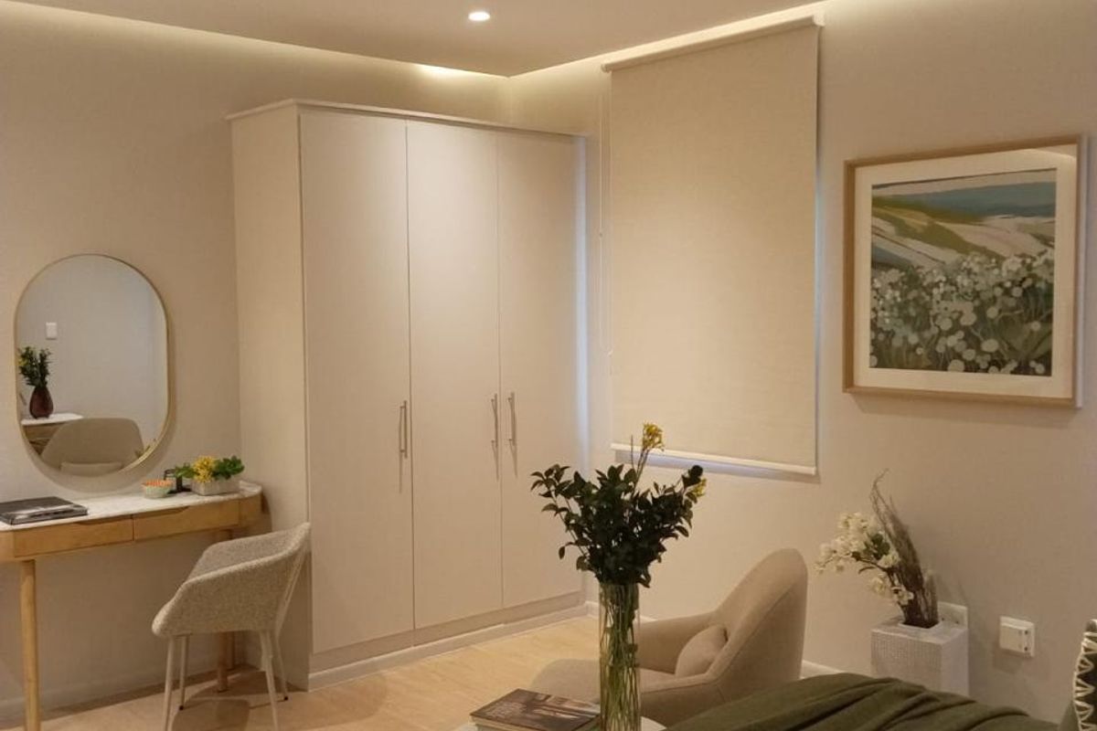 A well-maintained bedroom featuring neutral tones, built-in wardrobe storage, recessed ceiling lighting, and modern laminate flooring.