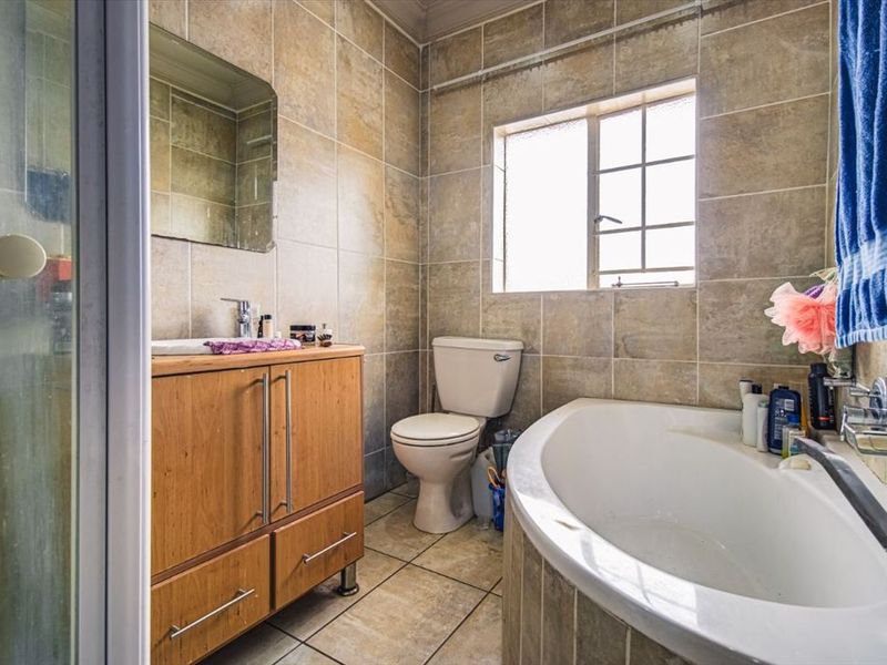 A functional bathroom featuring a vanity cabinet, bathtub, separate shower enclosure, and full-height wall tiling.