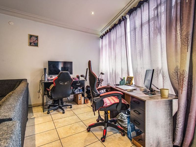 A functional home office space featuring tiled flooring, recessed lighting, and a large window allowing for natural light.