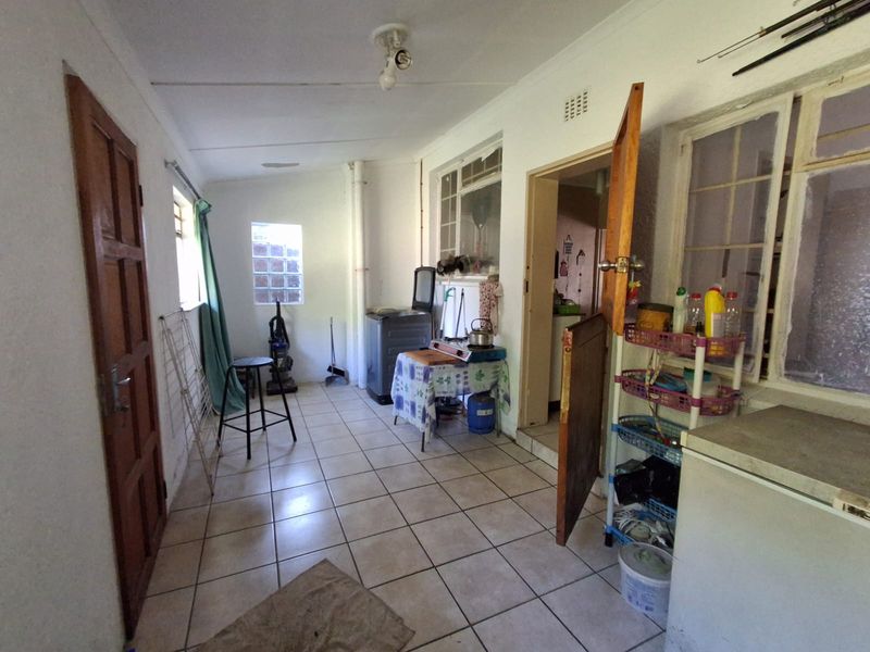 A functional laundry area featuring tiled flooring, natural light through glass block and casement windows, and direct access to adjacent living spaces.