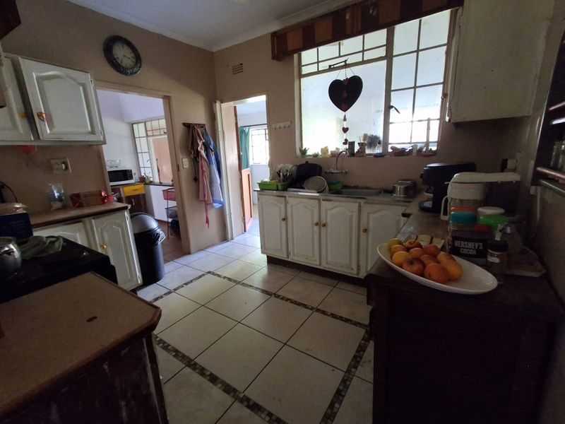 A dated kitchen featuring built-in cabinetry, tiled flooring, and a double sink, offering potential for a modern renovation.