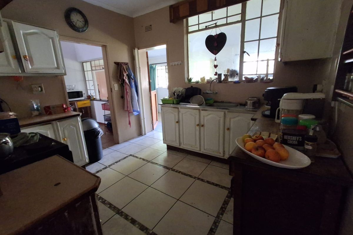 A dated kitchen featuring built-in cabinetry, tiled flooring, and a double sink, offering potential for a modern renovation.