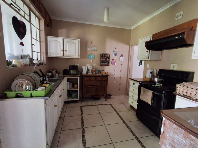A functional kitchen featuring built-in cabinetry, tiled flooring, and an extractor fan, offering a dated layout ready for modern updates and renovation.