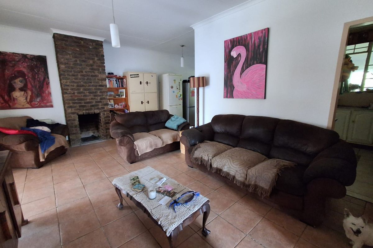 Spacious living room featuring a prominent exposed brick fireplace and durable ceramic tile flooring, offering a comfortable and functional layout.