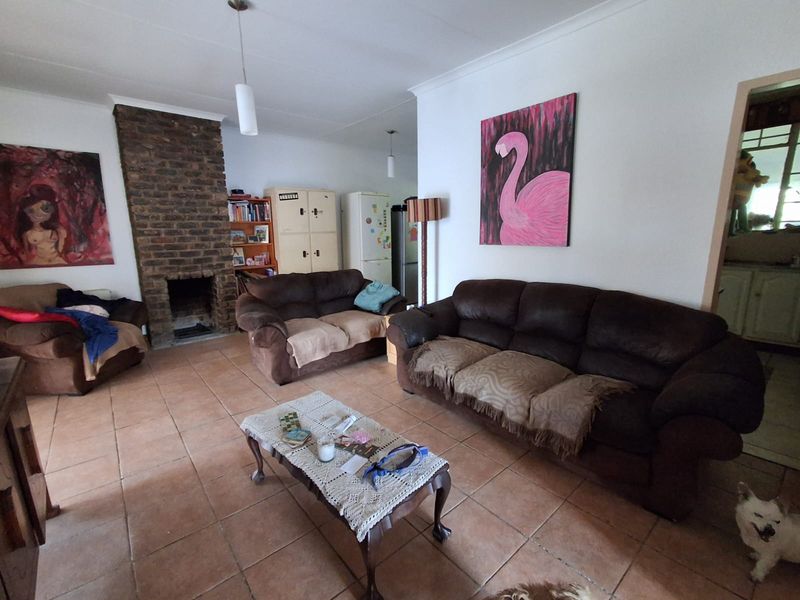Spacious living room featuring a prominent exposed brick fireplace and durable ceramic tile flooring, offering a comfortable and functional layout.