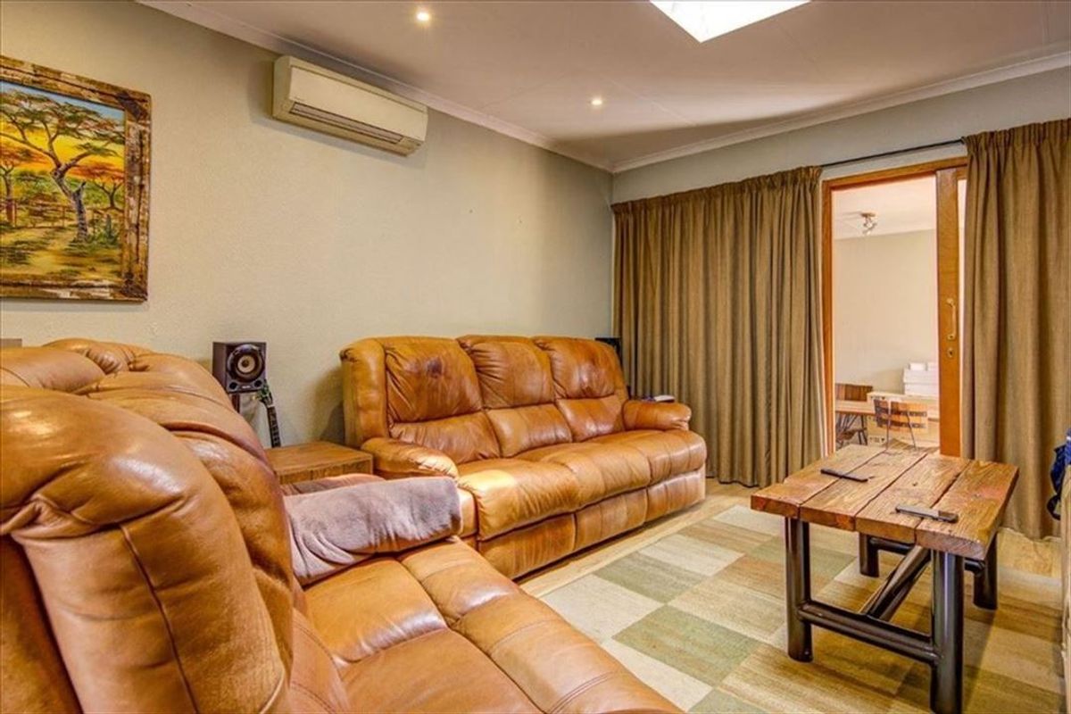 A comfortable living room featuring a split-system air conditioner, recessed downlighting, and a sliding glass door providing access to an adjacent space.