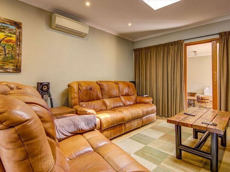 A comfortable living room featuring a split-system air conditioner, recessed downlighting, and a sliding glass door providing access to an adjacent space.