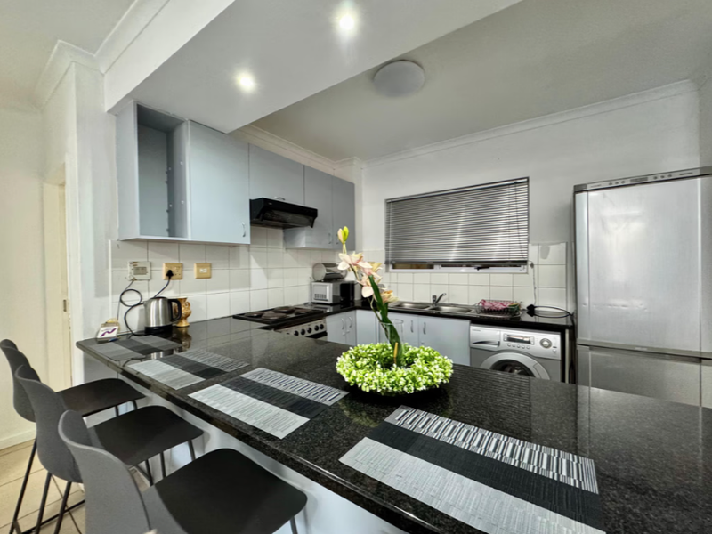 A functional kitchen featuring granite countertops, a breakfast bar, built-in cabinetry, and integrated appliances, offering a practical layout for daily use.