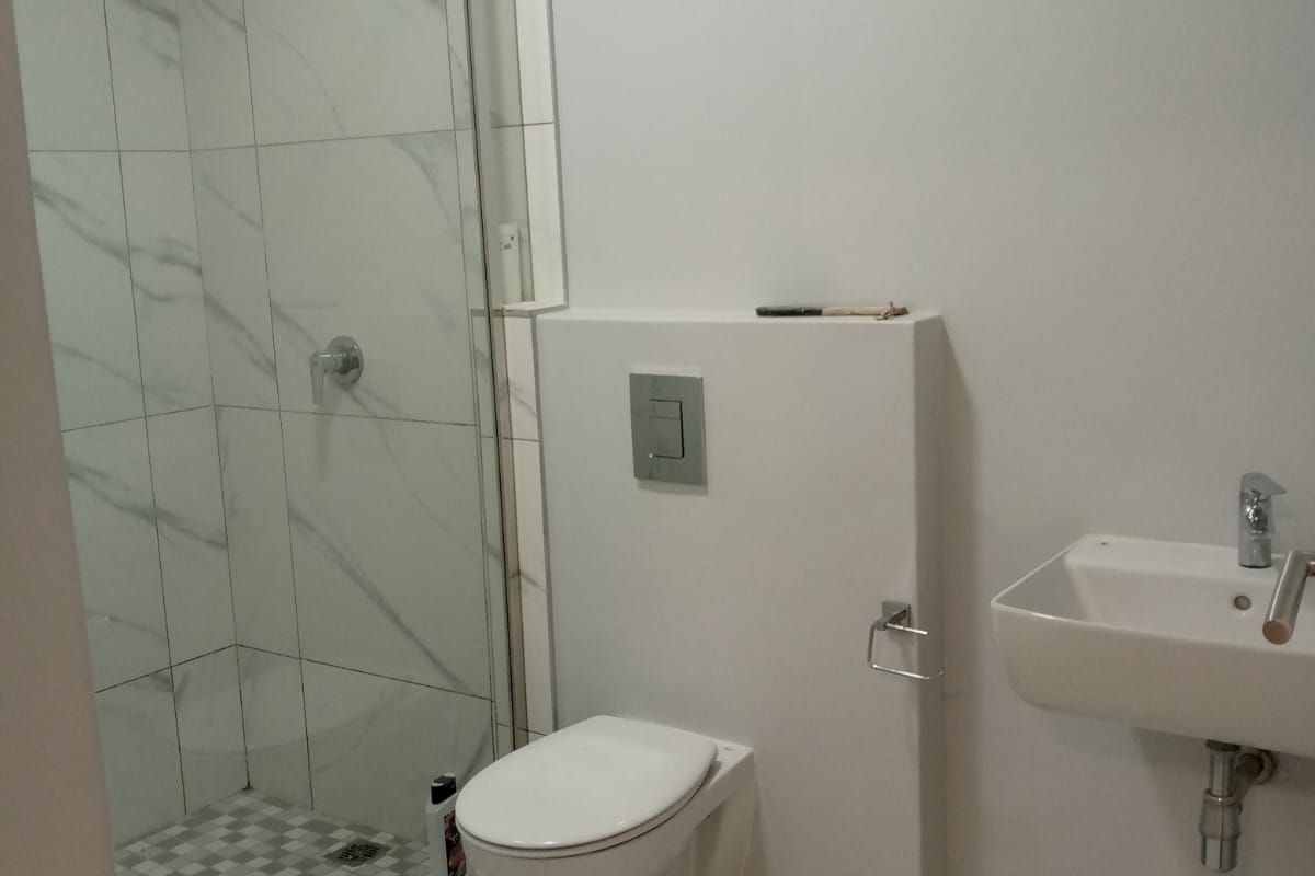 Modern bathroom featuring a walk-in shower with marble-look tiles, a wall-mounted toilet with concealed cistern, and a wall-mounted basin.