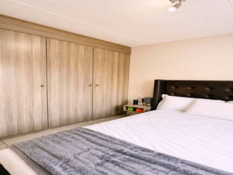 A well-maintained bedroom featuring extensive floor-to-ceiling built-in wooden wardrobes providing ample storage space.