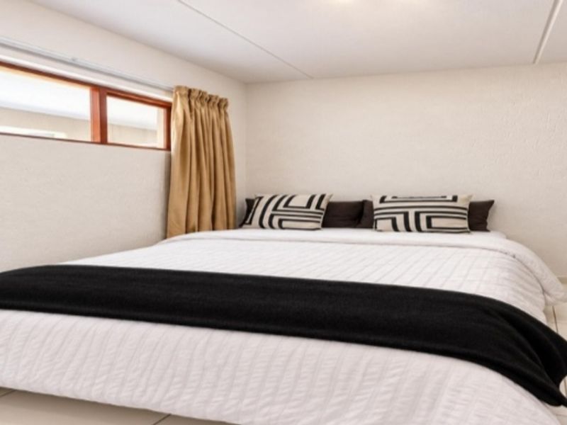 A bedroom featuring tiled flooring and timber-framed windows, providing a neutral and functional space.