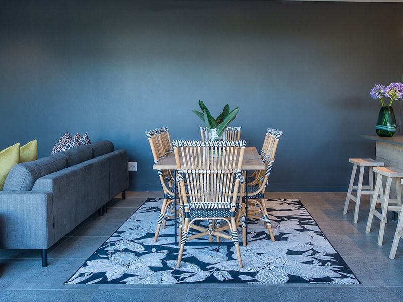 Modern open-plan living and dining area featuring tiled flooring, a breakfast bar, and a bold dark accent wall.