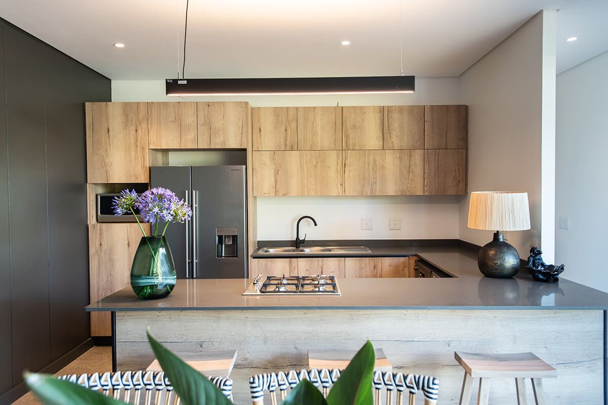 Modern kitchen featuring wood-grain cabinetry, stone countertops, a central gas cooktop, and integrated lighting, offering a sleek and functional culinary space.