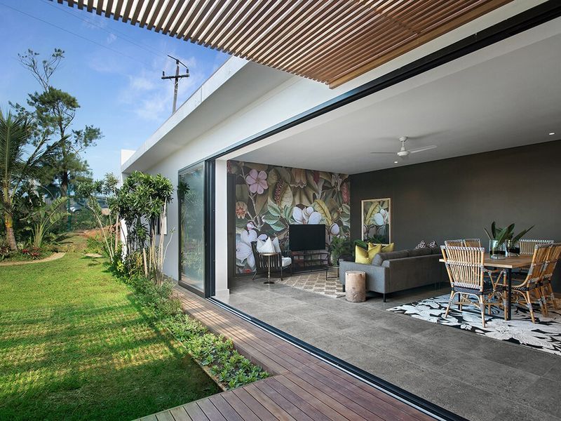 Modern open-plan living and dining area featuring large sliding glass doors that open onto a timber deck and garden.