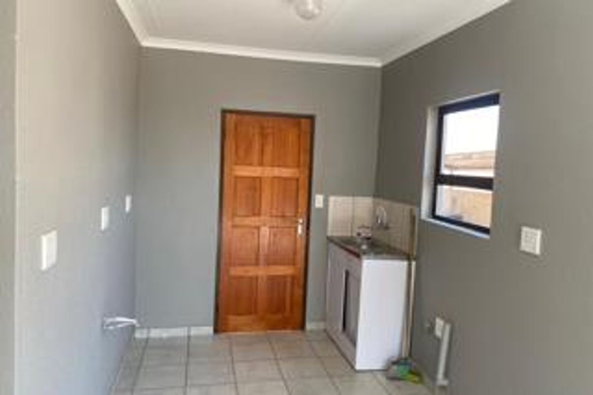 A functional laundry area featuring tiled flooring, a single basin sink, and plumbing connections for laundry appliances.