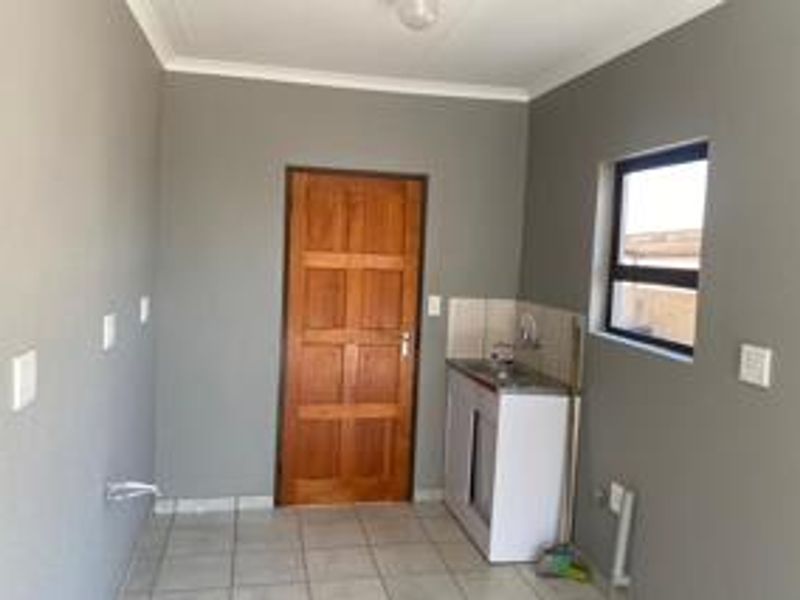 A functional laundry area featuring tiled flooring, a single basin sink, and plumbing connections for laundry appliances.