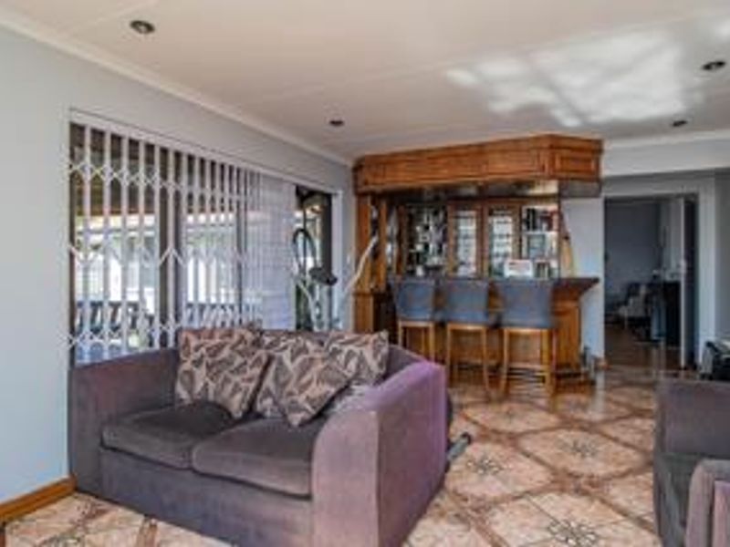 A living area featuring a built-in wooden bar with integrated shelving and tiled flooring, providing a dedicated space for entertainment.