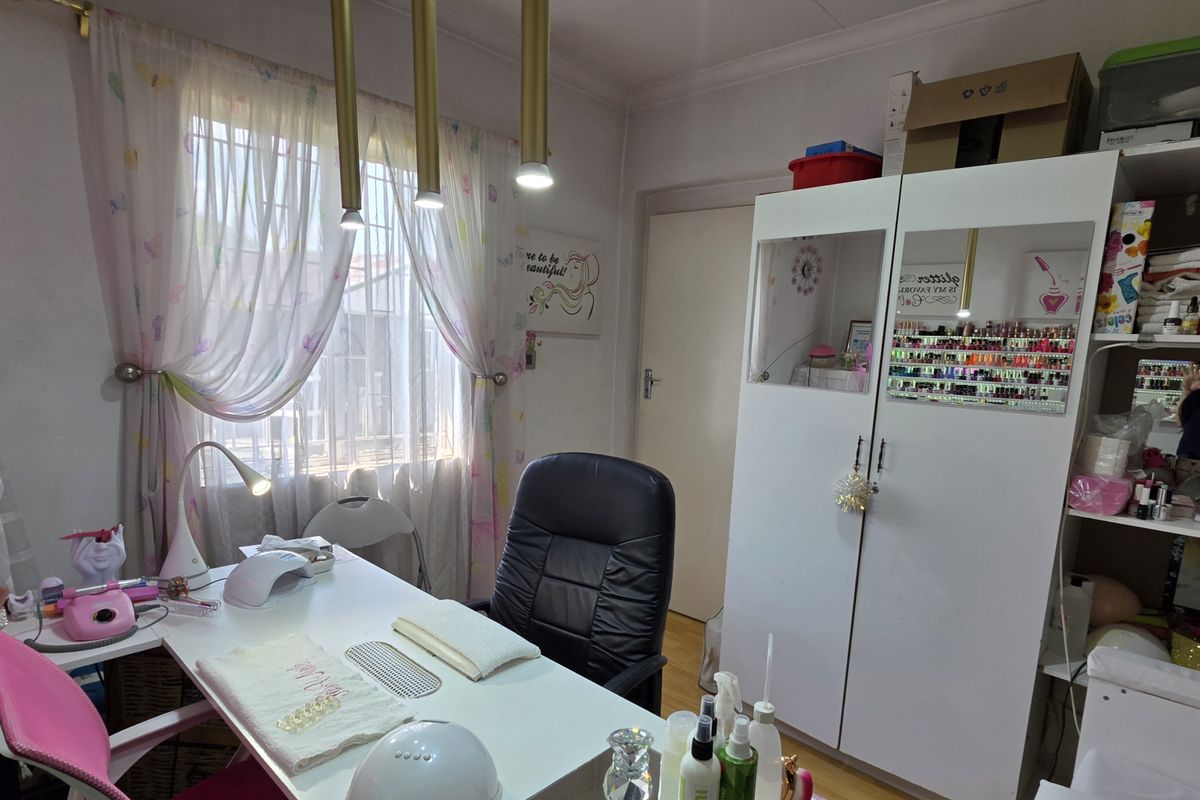 A bedroom currently utilized as a home salon, featuring laminate flooring, built-in cupboard storage, and pendant lighting.