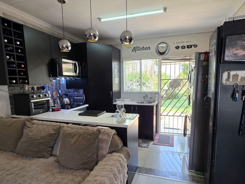Open-plan kitchen area featuring dark cabinetry, built-in microwave, wine storage, and direct access to the rear garden through a security gate.
