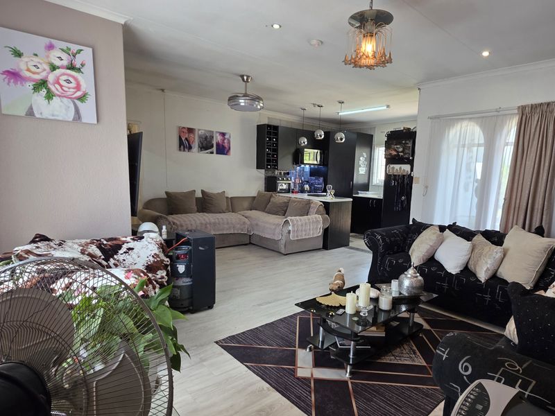 Spacious open-plan living area featuring laminate flooring, recessed lighting, and a modern kitchen with built-in cabinetry and a central island.