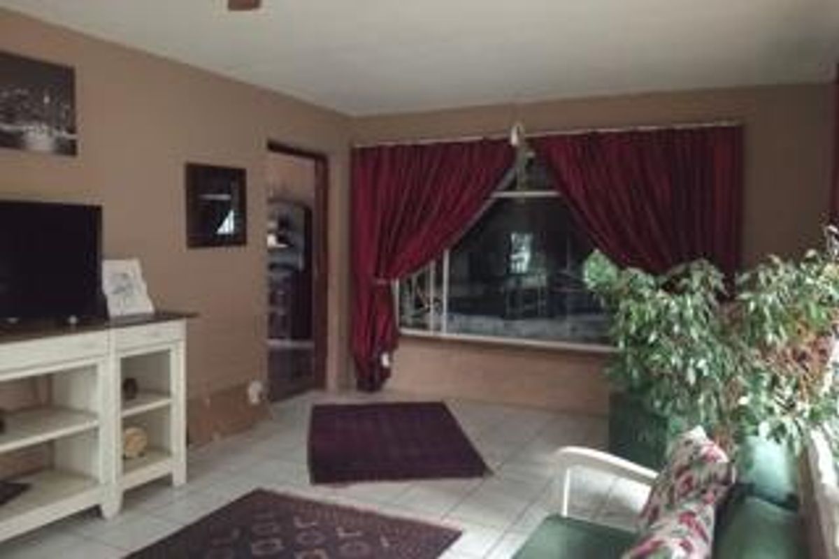 A living room featuring tiled flooring, a large window with curtains, and a ceiling fan, offering a functional space for relaxation.