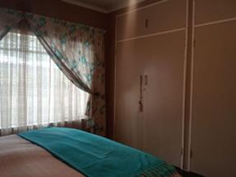 A bedroom featuring built-in cupboards and a window with natural light.