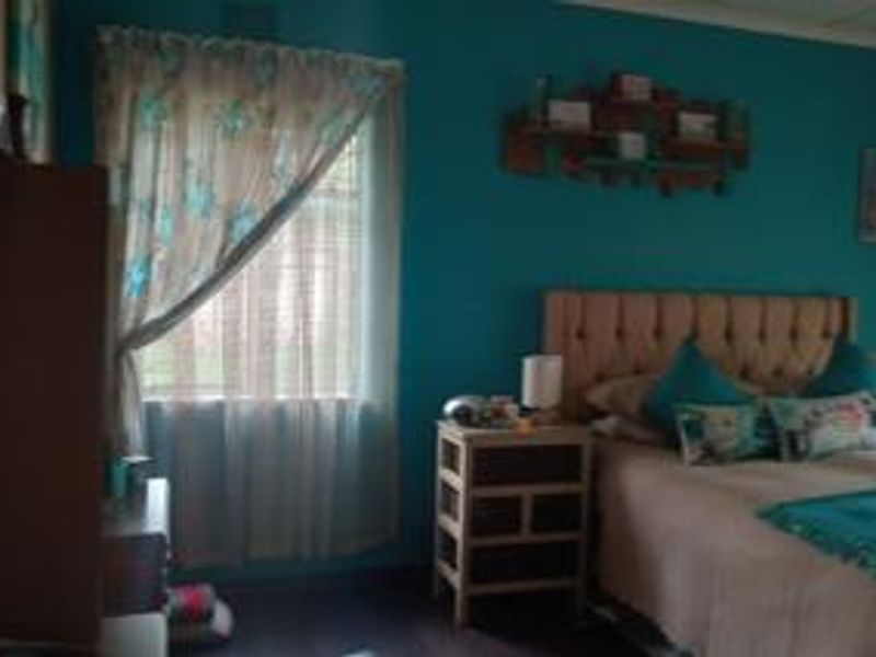 A bedroom featuring teal painted walls and a window with curtains.