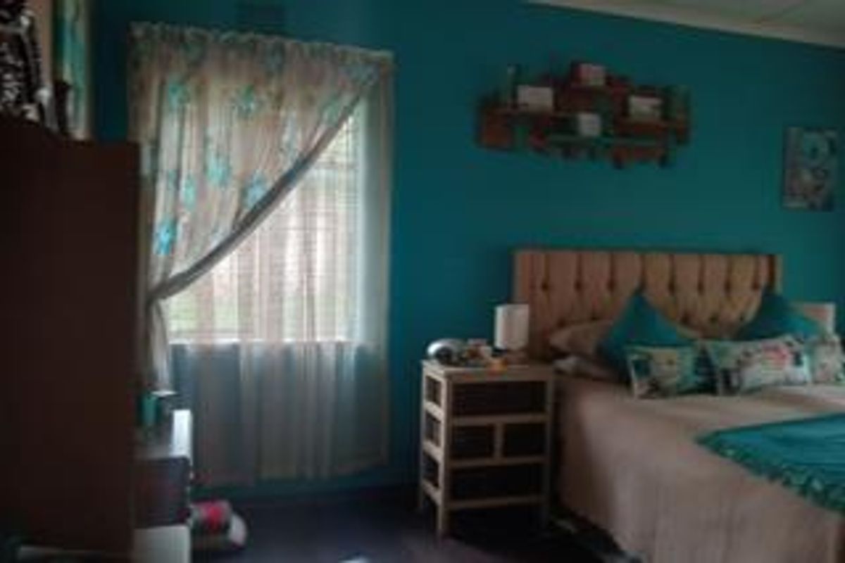 A bedroom featuring teal painted walls and a window with curtains.