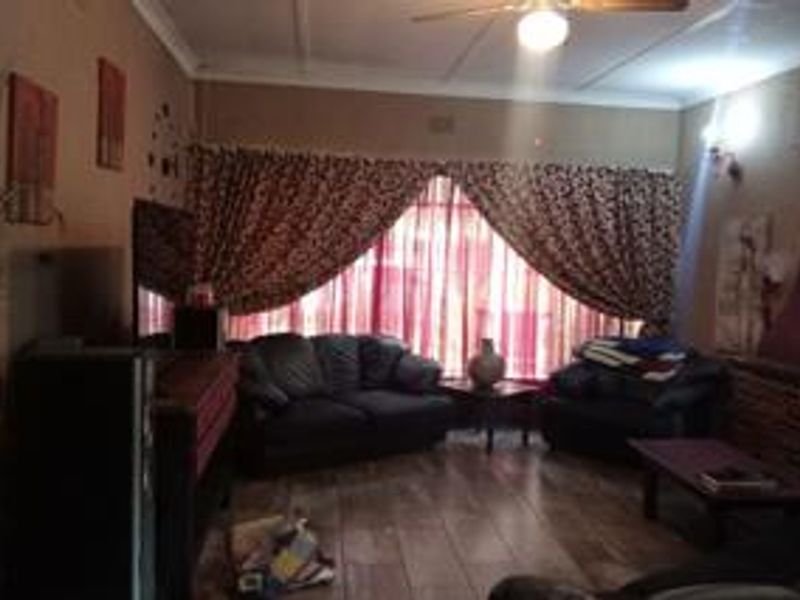 A living room featuring tiled flooring, a ceiling fan, and decorative coving, providing a functional space for relaxation.