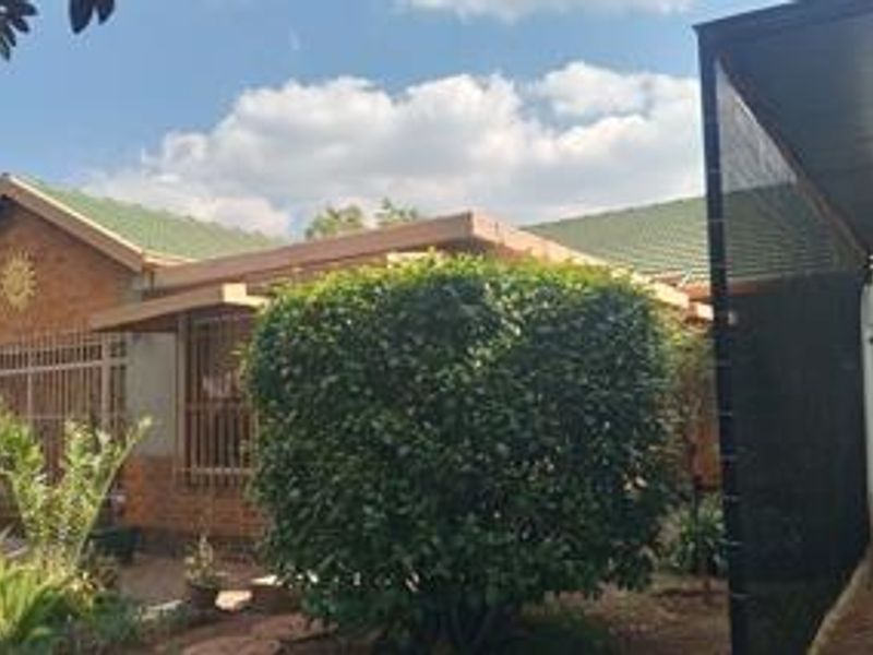 Front view of a brick house featuring a tiled roof, security bars on windows, and an attached carport structure.