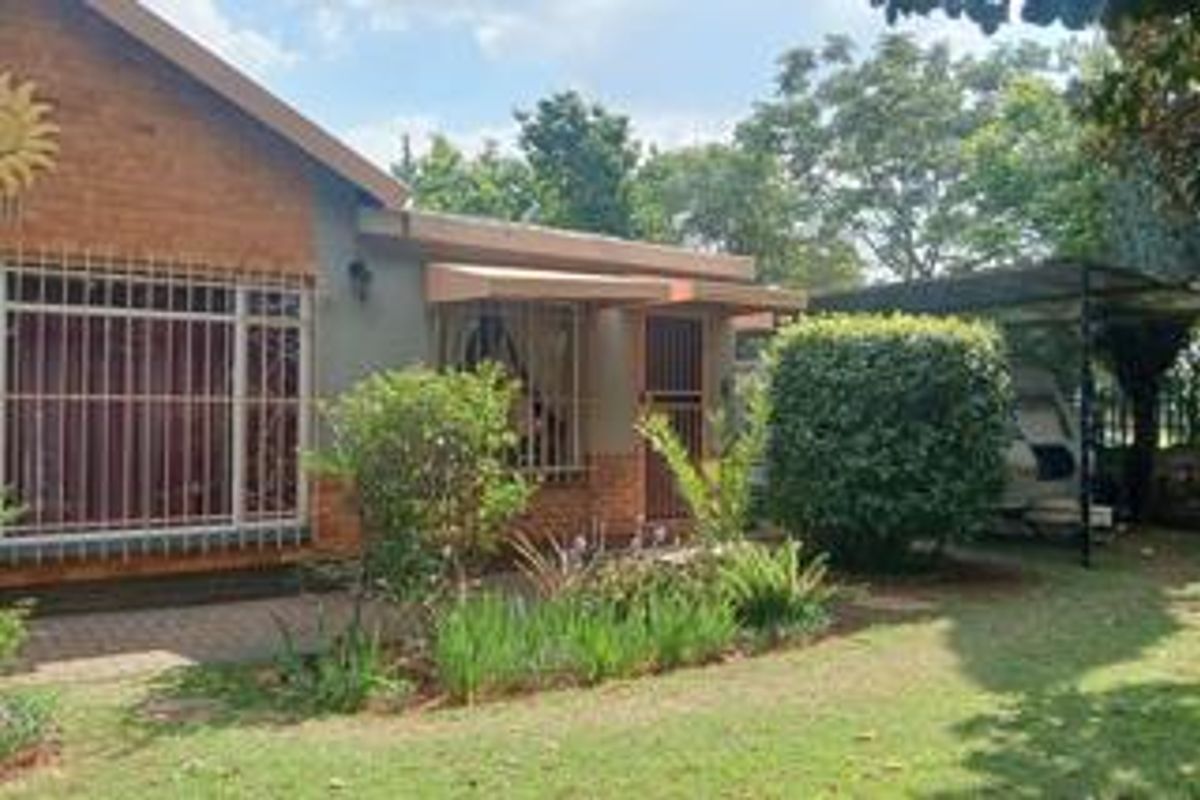 Front elevation of a face brick house featuring security bars on windows, a paved walkway, and an attached carport structure.