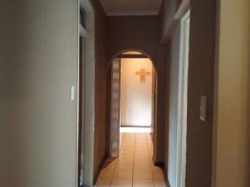 A simple interior hallway featuring tiled flooring and an arched transition leading to another area of the home.