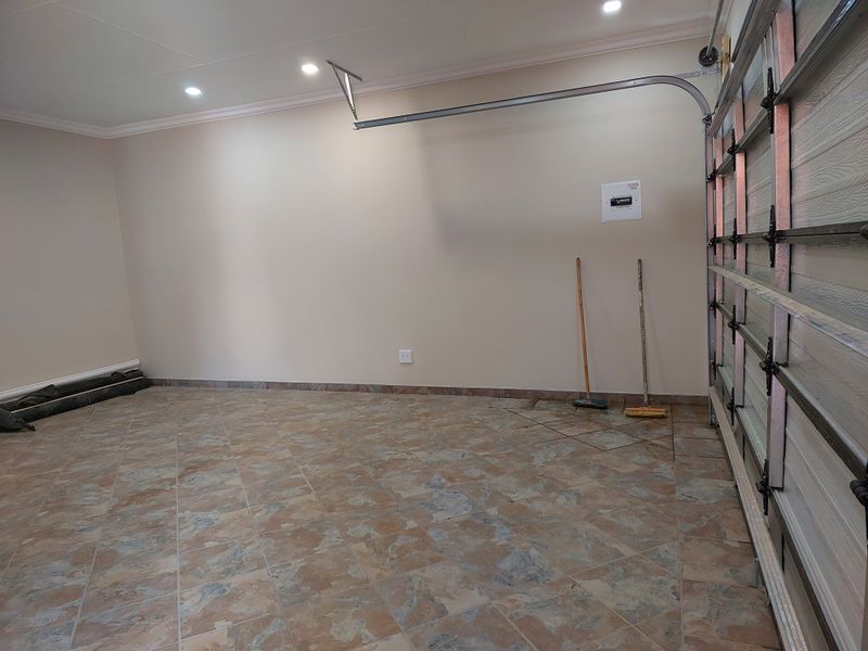 A clean and well-maintained garage featuring tiled flooring, recessed downlighting, and a functional sectional garage door.
