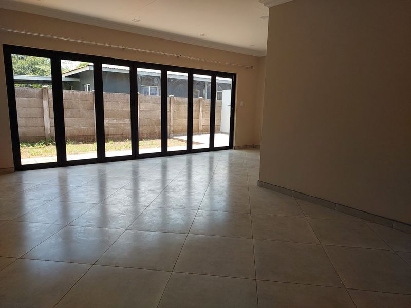 Spacious, empty living area featuring large folding glass doors that provide abundant natural light and direct access to the rear garden.