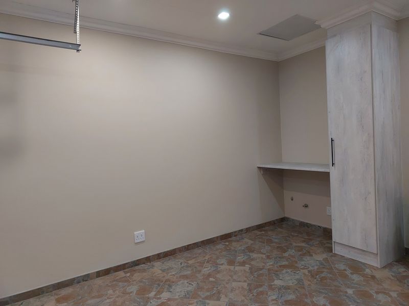 A clean, functional laundry area featuring tiled flooring, built-in cabinetry, and a dedicated countertop with plumbing connections for appliances.
