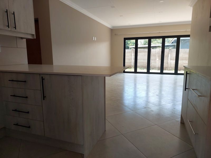 Spacious open-plan living area featuring modern kitchen cabinetry, tiled flooring, and large bi-fold doors leading to the rear exterior.