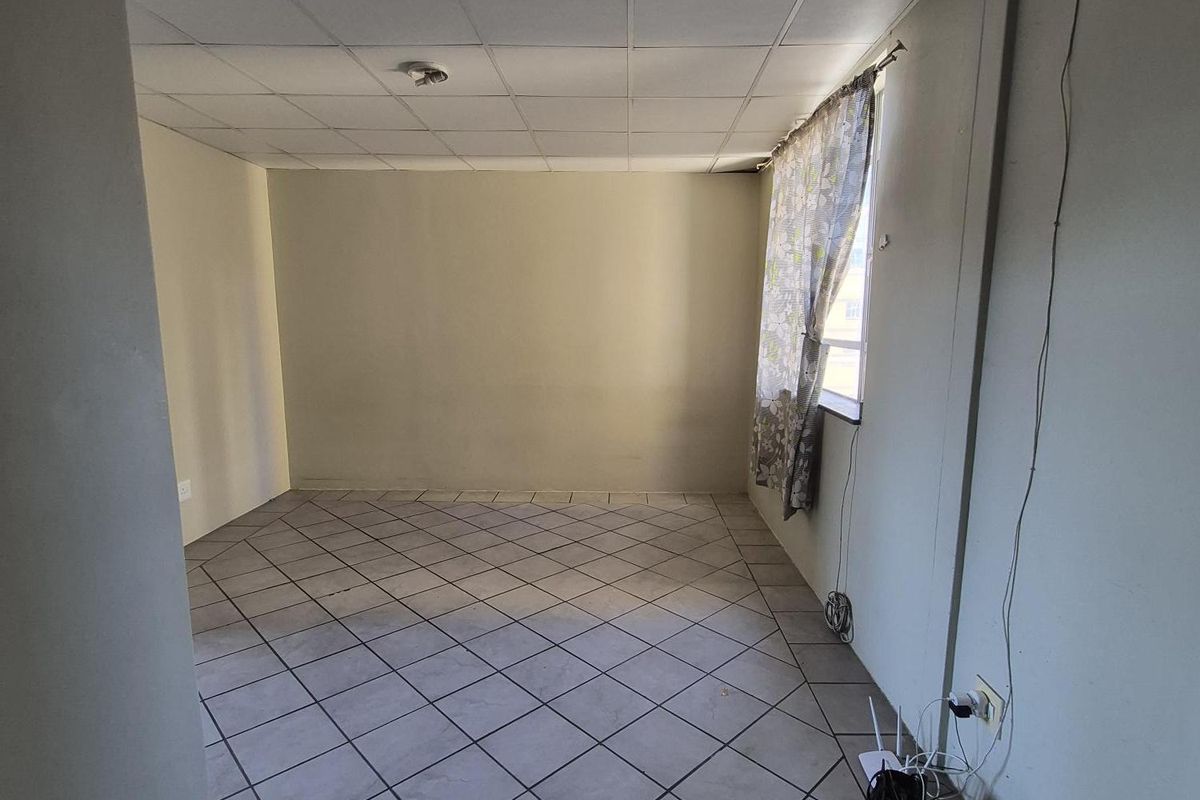 An empty living room featuring ceramic tile flooring and a drop ceiling, offering a blank canvas for renovation and interior design updates.
