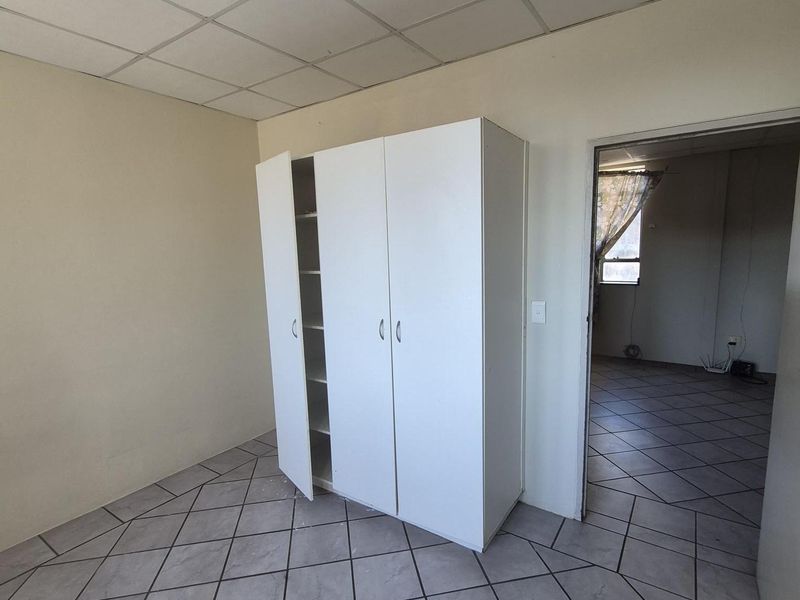 A vacant bedroom featuring tiled flooring, a suspended ceiling, and a built-in wardrobe, requiring minor repairs to the ceiling and lighting.