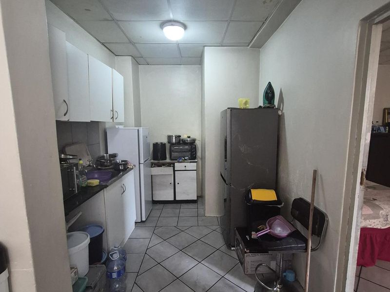 A compact kitchen featuring tiled flooring, built-in cabinetry, and a drop ceiling, offering a functional layout that could benefit from cosmetic updates.