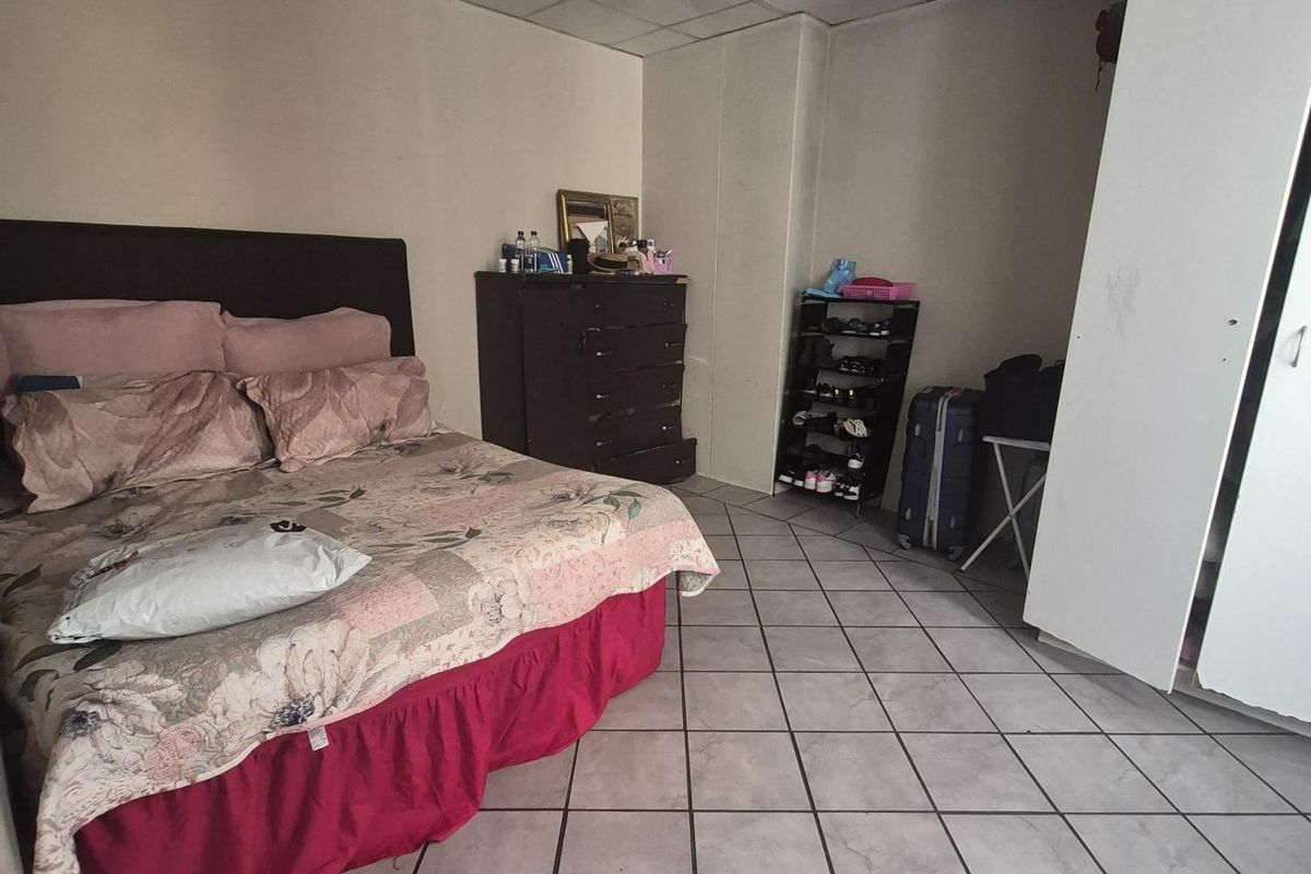 A bedroom featuring tiled flooring and a drop ceiling with integrated lighting. The space requires cosmetic updates to improve its overall condition.
