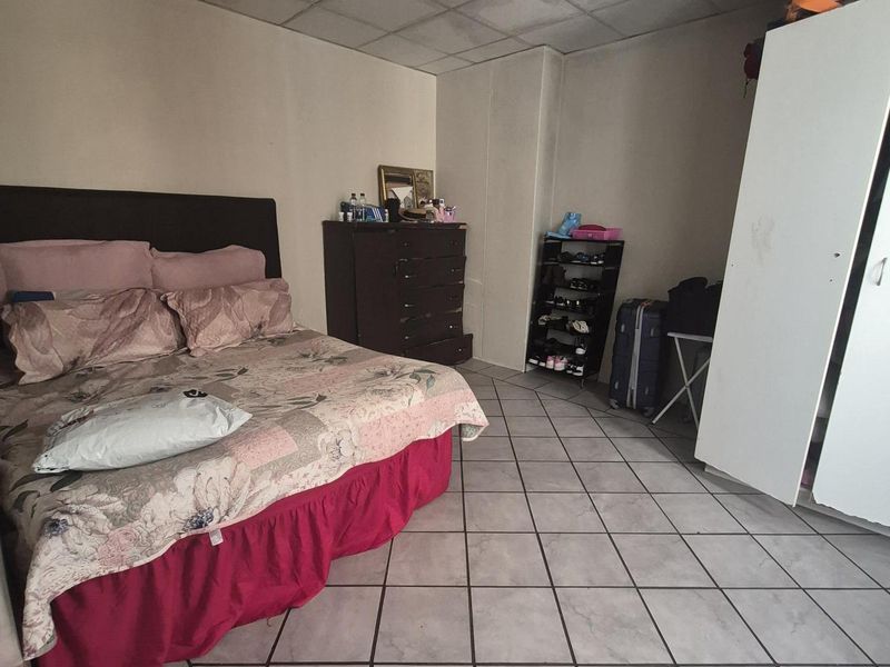 A bedroom featuring tiled flooring and a drop ceiling with integrated lighting. The space requires cosmetic updates to improve its overall condition.