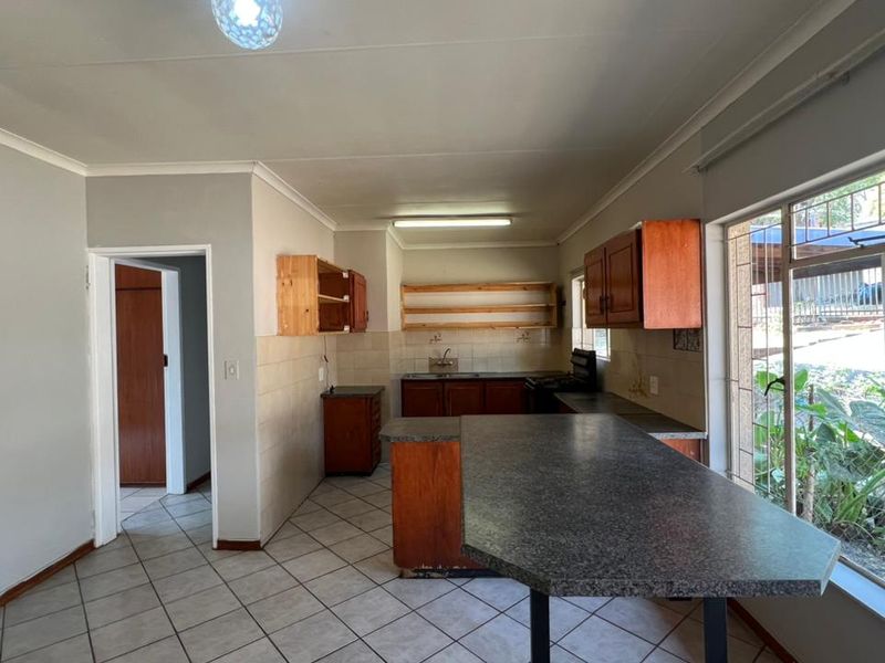 A functional kitchen space featuring tiled flooring, built-in cabinetry, a breakfast bar, and a tiled backsplash, offering potential for modern updates.